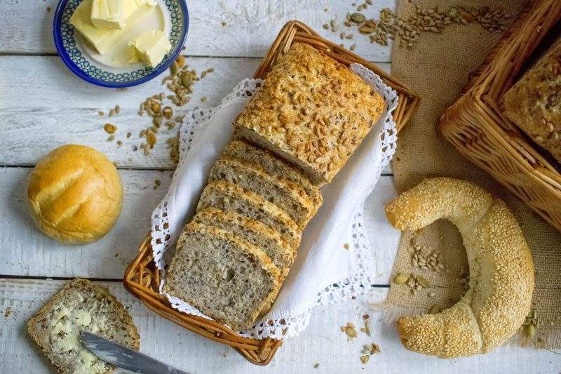 Na zdjęciu widać chleb pszenny na zakwasie, pokrojony w kromki i ułożony w koszyku. Widoczne są ziarna słonecznika, dyni i siemienia lnianego, którymi wzbogacony jest nasz pełnoziarnisty chleb,.